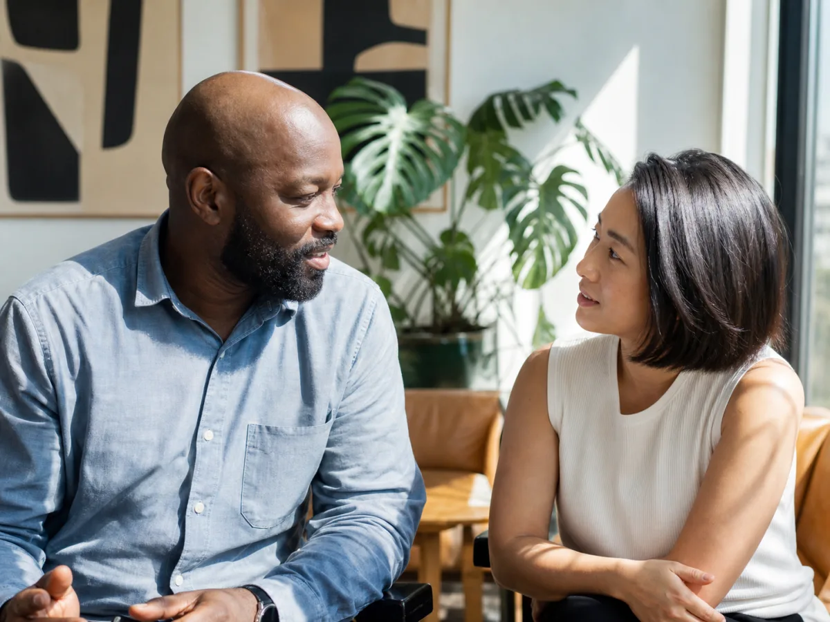Two colleagues in a warm, human conversation at work
