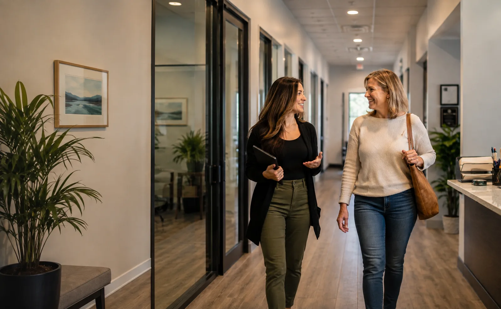 Two people walking and talking together down an office hallway